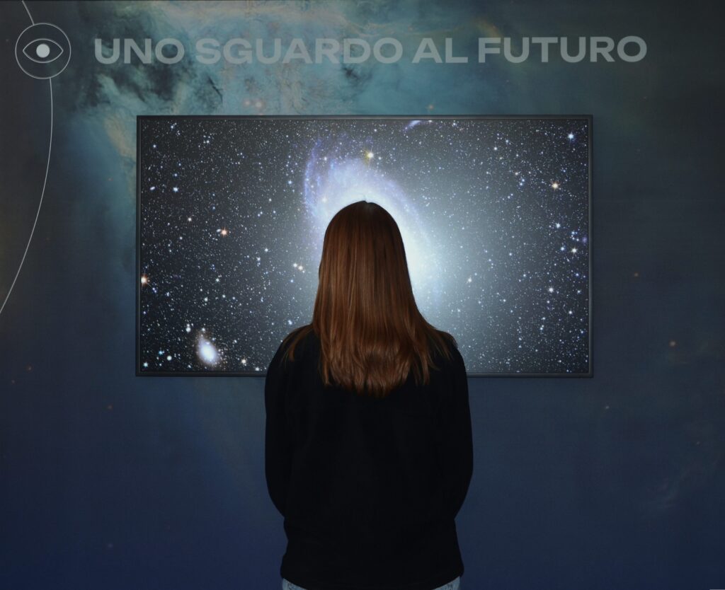 Ragazza vista di spalle mentre fruisce i contenuti della mostra "Osservatori del cielo". 